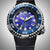 Montre pour homme en gros plan avec cadran bleu-violet, lunette argentée et bracelet noir.