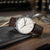 Montre pour homme sur table : bracelet en cuir marron, cadran blanc avec index et logo