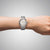 Armbanduhr am Handgelenk mit elfenbeigfarbenem Zifferblatt und Edelstahlband