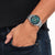 Montre bracelet pour homme au poignet avec cadran vert et bracelet en acier inoxydable argenté.