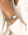 Armbanduhr am Handgelenk mit silbernem Maschenband und rechteckigem Zifferblatt
