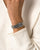 Damenarmbanduhr am Handgelenk mit silbernem Edelstahlgliederarmband und rechteckigem schwarzem Zifferblatt