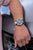 Montre bracelet pour homme au poignet avec cadran noir et bracelet en métal.
