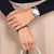 Montre pour femme au poignet avec bracelet en métal argenté et cadran blanc.