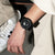 Montre homme avec boîtier noir et bracelet noir, portée au poignet