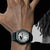 G-Shock Herrenuhr am Handgelenk mit schwarzem Armband und silbernem, sichtbarem Zifferblatt.