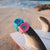 Pink- und türkisfarbene digitale G-SHOCK Uhren nebeneinander auf Deck