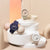 Casio G‑SHOCK Damenarmbanduhr in Weiß auf Podest, rundes Gehäuse mit roségoldenen Akzenten