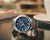 Casio G-Shock Herrenuhr 3/4-Ansicht mit blauem Zifferblatt und silbernem Metallarmband