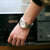 Nahansicht am Handgelenk: Armbanduhr mit goldfarbenem Metallband und weißem Zifferblatt