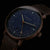 Montre homme avec cadran bleu, aiguilles dorées et bracelet en cuir marron.