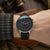 Montre pour homme au poignet : cadran noir, bracelet en cuir noir avec détails rouges