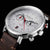 Montre homme de face, gros plan : cadran blanc, bracelet en cuir marron, touches rouges, chronographe