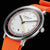 Montre pour homme en gros plan : bracelet orange, cadran blanc avec anneau des minutes encadré