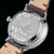 Fond de montre pour homme en vue oblique : boîtier argenté avec motif de ville, bracelet en cuir marron.