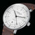 Gros plan d'une montre pour homme : boîtier argenté, cadran blanc, bracelet en cuir marron.