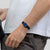 Damenuhr am Handgelenk mit blauem Zifferblatt und schwarzem Armband, über dunkler Hose