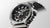 Nahansicht: Herrenuhr mit schwarzem Zifferblatt, Zifferblattstruktur und Titanarmband