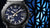 Casio MR-G Herrenuhr Nahaufnahme: blaues Zifferblatt, goldene Zeiger, schwarzes Schutzgehäuse.