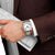 Montre pour homme au poignet avec cadran blanc, aiguilles rouges et bracelet en acier inoxydable