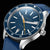 Montre bracelet pour homme, gros plan sur cadran bleu avec aiguilles, lunette argentée et bracelet bleu.