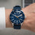 Montre bracelet pour homme au poignet, cadran bleu avec index luminescents, boîtier argenté.
