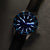 Montre pour homme avec cadran bleu, index luminescents et boîtier argenté, bracelet bleu.