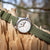 Montre homme avec boîtier argenté, cadran blanc et bracelet en toile verte sur le côté