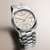 Herrenarmbanduhr seitlich, beiges Zifferblatt mit Indexen und Datumsfenster