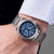 Montre bracelet pour homme au poignet avec cadran bleu, bracelet en métal argenté et couronne