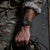Montre bracelet pour homme au poignet d'une personne en camouflage, bracelet vert olive et aiguilles lumineuses