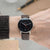 Montre pour homme au poignet avec cadran noir et bracelet en cuir marron.