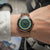 Montre homme avec bracelet en métal couleur or rose, cadran vert et index marqués