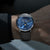 Montre pour homme au poignet : cadran bleu, bracelet en cuir noir, boîtier argenté.