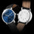 Montre homme : cadran et fond bleus avec gravure de cercle, bracelet en cuir marron.