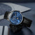 Montre homme en angle : cadran bleu, bracelet en cuir noir.