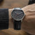 Montre bracelet pour homme au poignet avec bracelet en cuir noir et cadran sombre