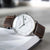 Montre homme vue de face : cadran blanc, bracelet en cuir marron et boîtier argenté