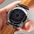 Montre avec cadran à rayures foncées, boîtier argenté et bracelet en cuir marron