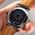Montre homme avec cadran sombre, bracelet en cuir marron et boîtier argenté
