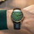 Montre homme au poignet avec cadran vert, boîtier doré et bracelet en cuir noir