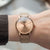 Montre pour femme au poignet : bracelet en maille couleur or rose, cadran beige, aiguilles