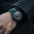 Herrenarmbanduhr am Handgelenk, schwarz-dunkelgrünes Zifferblatt, Kautschukband