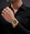Herrenuhr mit goldfarbenem Metallarmband und grünem Zifferblatt am Handgelenk