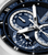 Detailansicht der Herrenuhr: blaues Zifferblatt, weiße Skalen, Zeiger und Edelstahlgehäuse