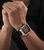 Herrenarmbanduhr am Handgelenk mit schwarzem Silikonarmband und goldfarbenem Gehäuse