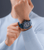 Herrenuhr am Handgelenk, blaues Silikonband und schwarzes Zifferblatt mit gelben Akzenten