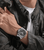 Police Herrenuhr am Handgelenk, schwarzes Silikonarmband und silbernes Gehäuse unter Jacke