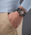 Herrenarmbanduhr am Handgelenk mit schwarzem Silikonband und skelettiertem Zifferblatt.
