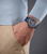 Herrenuhr mit blauem Silikonband am Handgelenk, rundes Glasgehäuse sichtbar